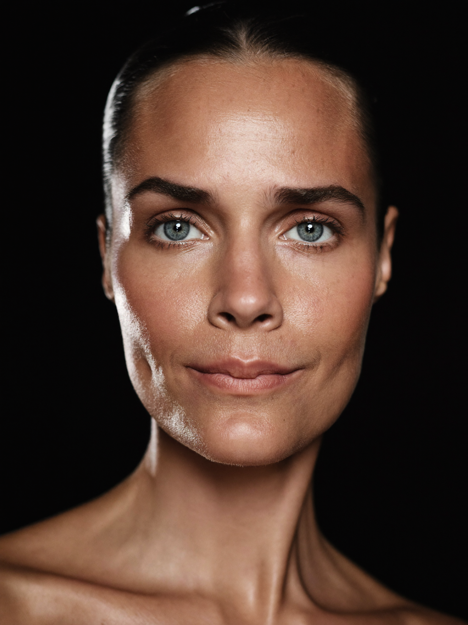 A confident woman in her late forties with bright, rested, naturally open eyes, lit against a dark background