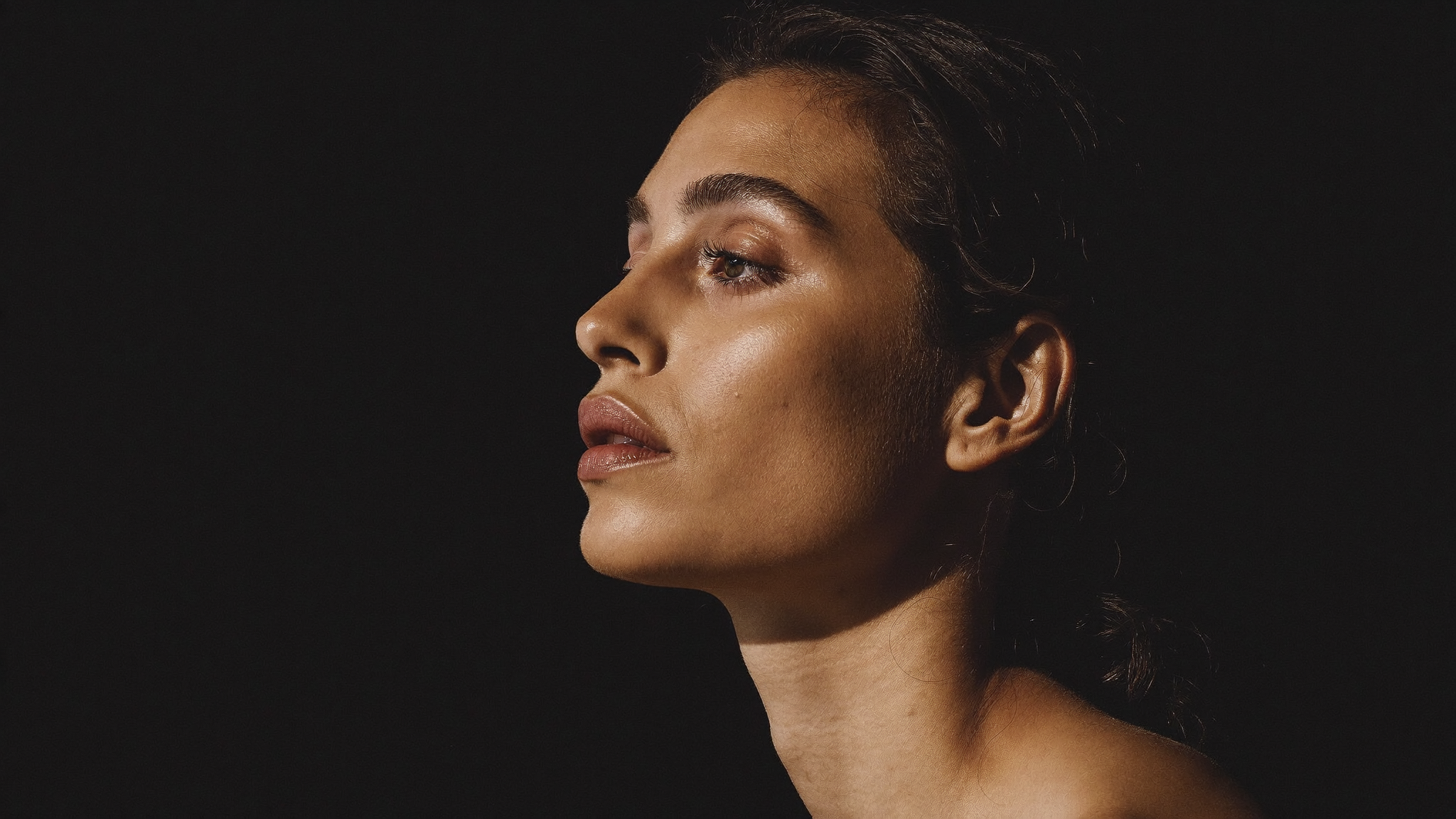 A poised woman in her late forties in profile, chin lifted, calm and rested, in dramatic editorial light