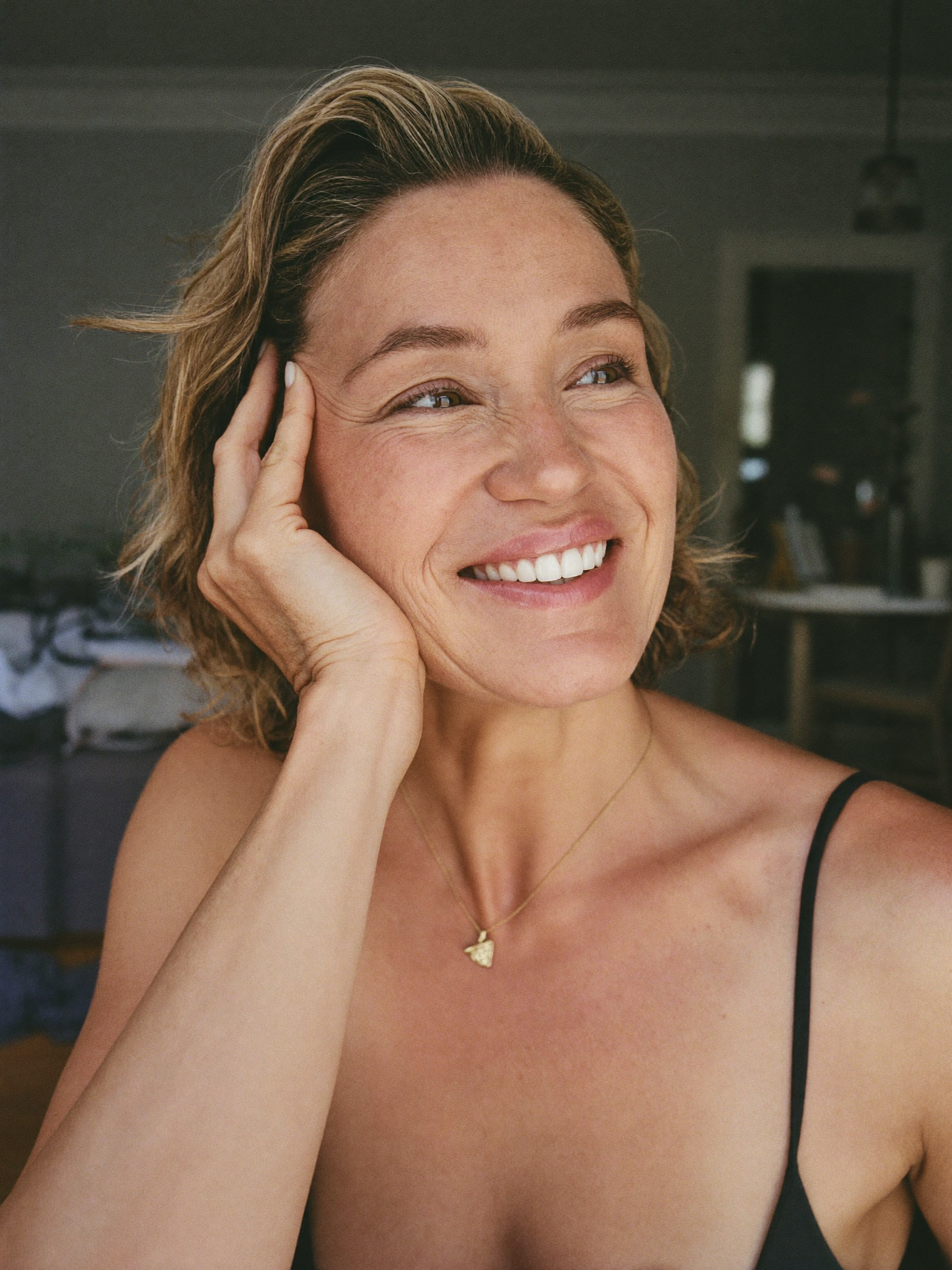 A relaxed woman in her mid fifties at home in soft daylight, looking rested and awake