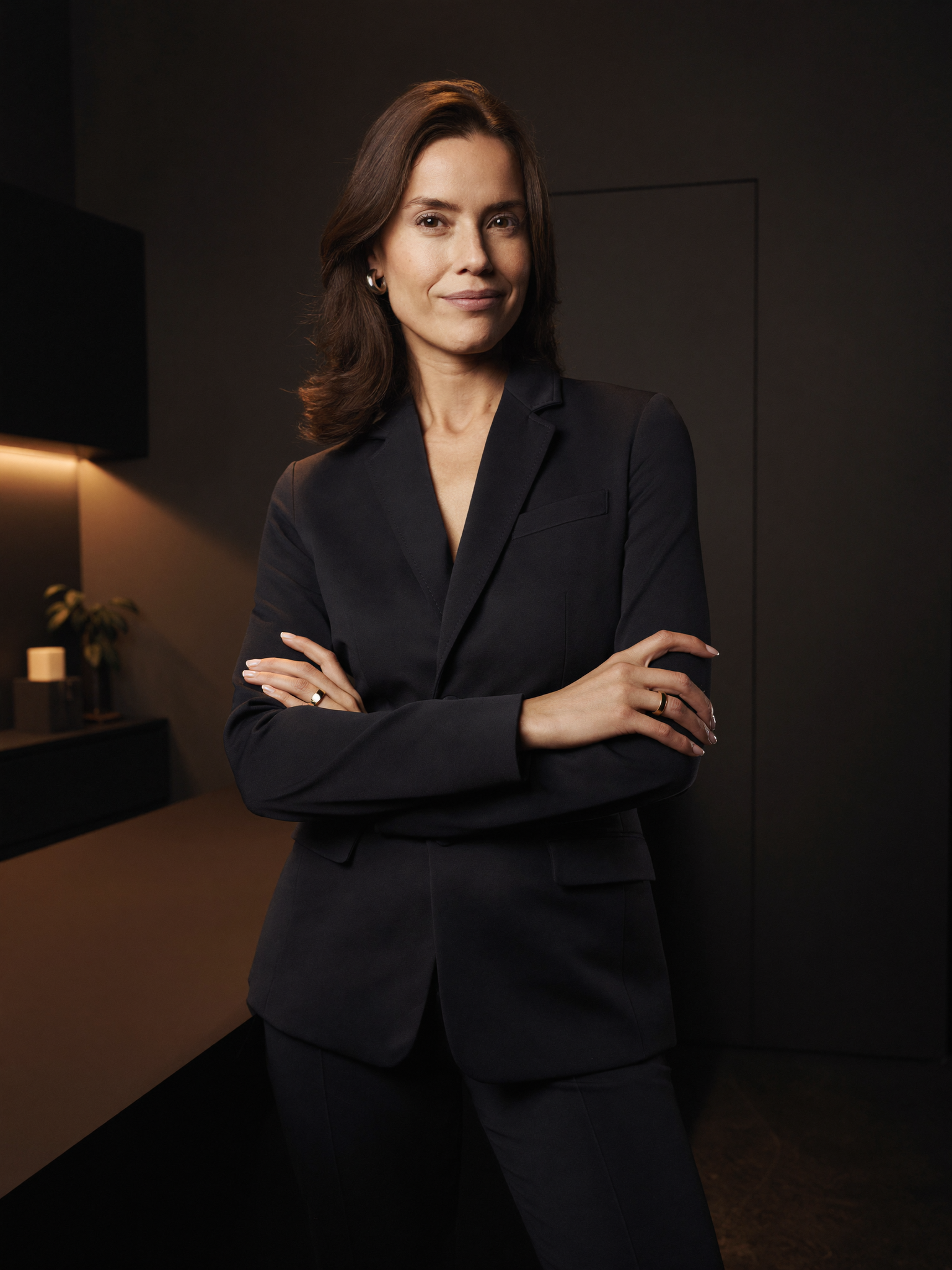 A board-certified eyelid and facial-plastic surgeon in a tailored dark blazer, standing in a modern consultation office