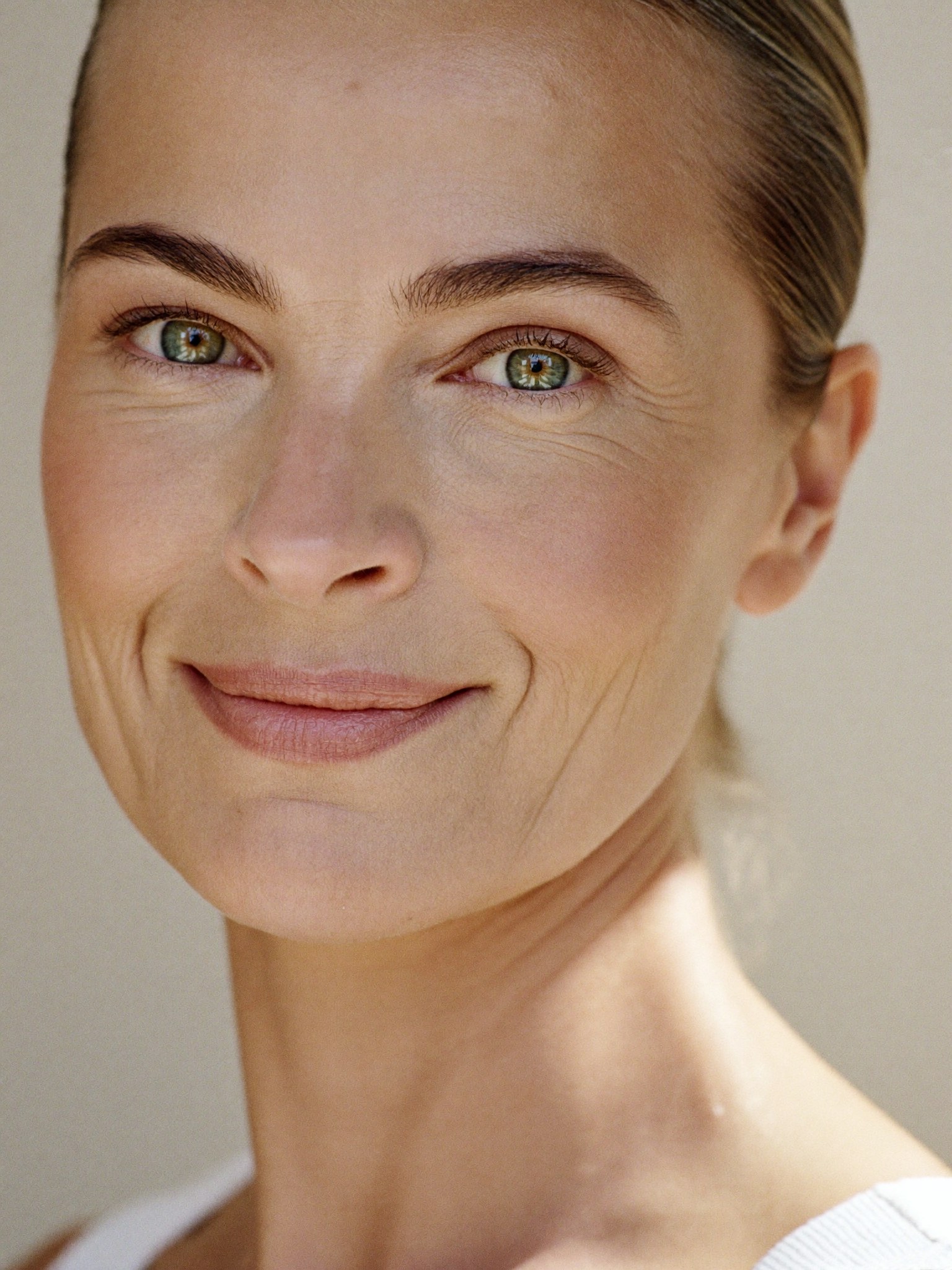 A refined woman in natural light with bright, open, rested eyes — the kind of natural, un-tired look a conservative eyelid refresh is designed to give.